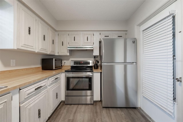 1198 E Hancock Dr, Deltona, FL 32725 - kitchen featuring appliances with stainless steel finishes, under cabinet range hood, light wood-style floors, white cabinetry, and a textured ceiling