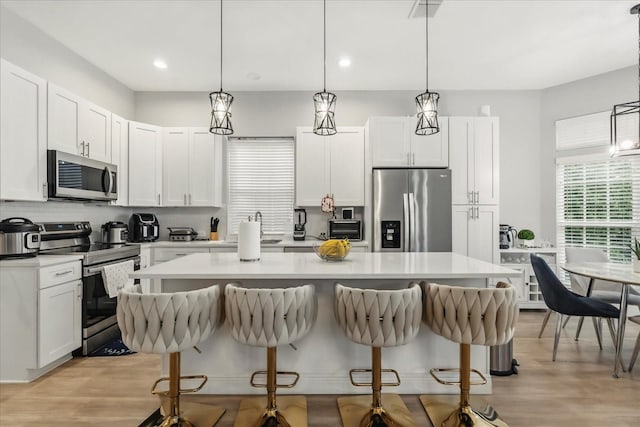 704 Honeysuckle Ave, Kissimmee, FL 34747 - kitchen with appliances with stainless steel finishes, a breakfast bar area, a kitchen island, light countertops, and recessed lighting