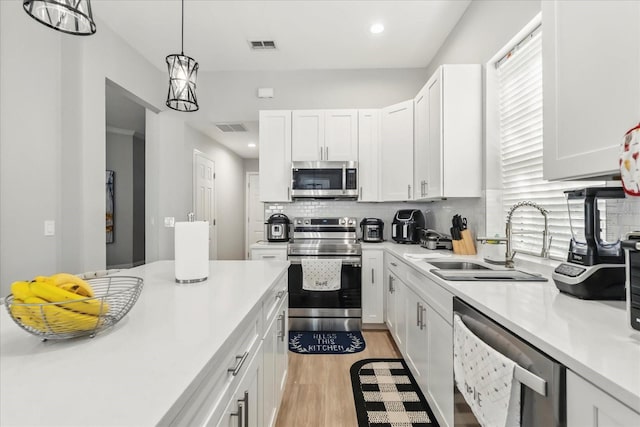 704 Honeysuckle Ave, Kissimmee, FL 34747 - kitchen with stainless steel appliances, a sink, light countertops, white cabinetry, and recessed lighting