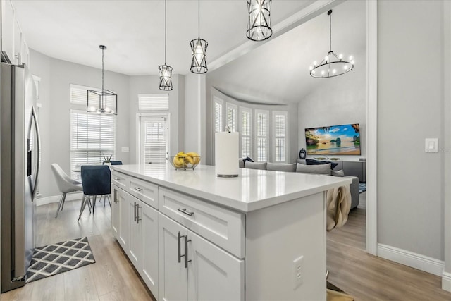 704 Honeysuckle Ave, Kissimmee, FL 34747 - kitchen with stainless steel fridge with ice dispenser, a chandelier, baseboards, white cabinetry, and light wood finished floors