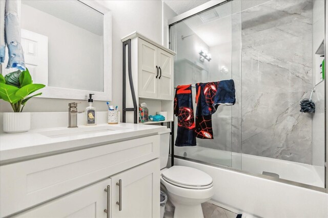 704 Honeysuckle Ave, Kissimmee, FL 34747 - bathroom with vanity, toilet, and bath / shower combo with glass door