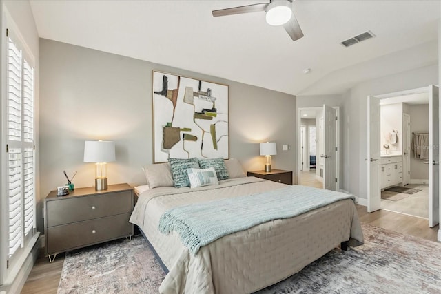 704 Honeysuckle Ave, Kissimmee, FL 34747 - bedroom featuring wood finished floors, multiple windows, vaulted ceiling, ensuite bath, and a ceiling fan