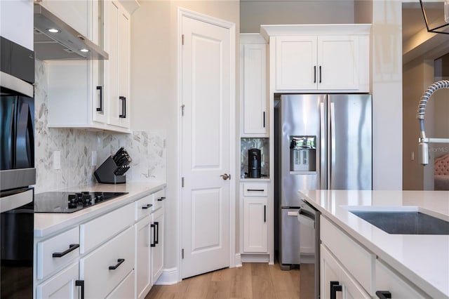 16489 Silver Brook Way, Winter Garden, FL 34787 - kitchen with appliances with stainless steel finishes, wall chimney range hood, light countertops, white cabinetry, and light wood finished floors
