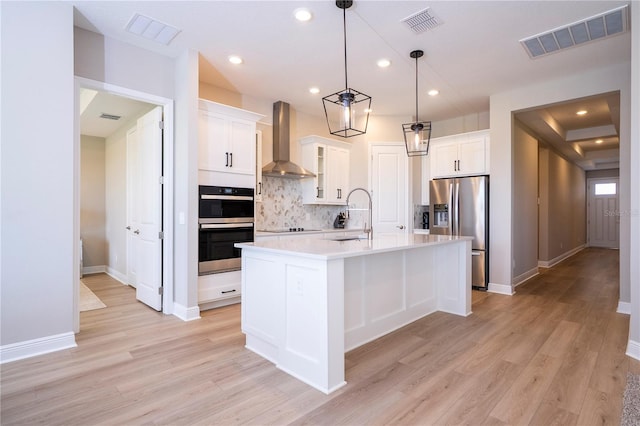 16489 Silver Brook Way, Winter Garden, FL 34787 - kitchen featuring wall chimney exhaust hood, a sink, stainless steel appliances, tasteful backsplash, and light wood-style floors