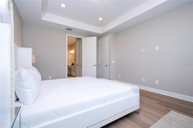 16489 Silver Brook Way, Winter Garden, FL 34787 - bedroom with a tray ceiling, wood finished floors, baseboards, recessed lighting, and ensuite bathroom