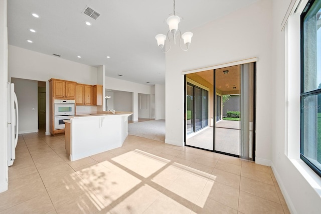 453 Sorrento Rd, Kissimmee, FL 34759 - kitchen with white appliances, open floor plan, light tile patterned floors, a chandelier, and baseboards