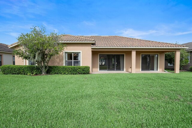 453 Sorrento Rd, Kissimmee, FL 34759 - rear view of property with a yard, stucco siding, and a tile roof
