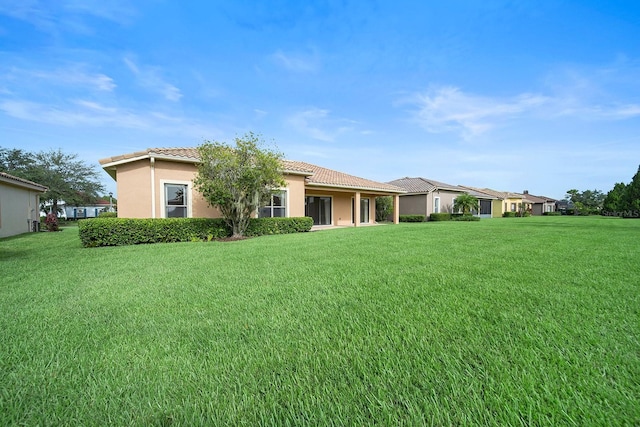 453 Sorrento Rd, Kissimmee, FL 34759 - back of house with a tiled roof, a lawn, and stucco siding