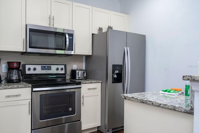 3229 Cupid Pl, Kissimmee, FL 34747 - kitchen with stainless steel appliances, decorative backsplash, white cabinets, and light stone countertops
