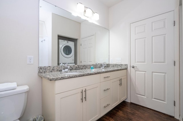 3229 Cupid Pl, Kissimmee, FL 34747 - bathroom featuring stacked washer and clothes dryer, double vanity, wood finished floors, and toilet