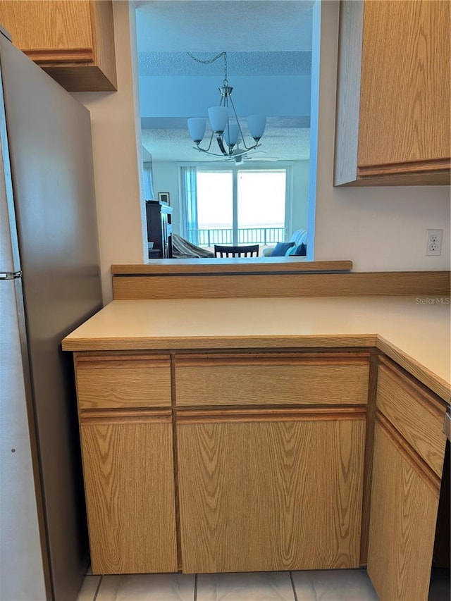 3360 Ocean Shore Blvd Unit 4050, Ormond Beach, FL 32176 - kitchen featuring freestanding refrigerator, light countertops, a chandelier, and light tile patterned floors