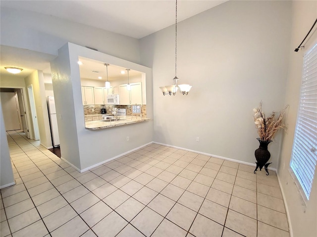 1108 Northlake Dr Unit 1108, Sanford, FL 32773 - kitchen with white appliances, a chandelier, backsplash, white cabinets, and light tile patterned floors