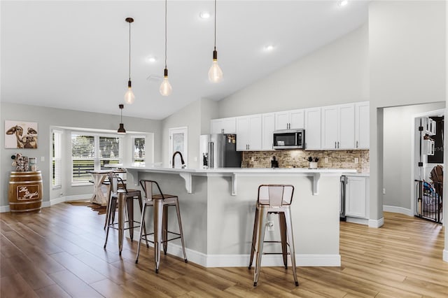 5478 NW 153rd Ct, Morriston, FL 32668 - kitchen with appliances with stainless steel finishes, a kitchen breakfast bar, white cabinets, light countertops, and high vaulted ceiling