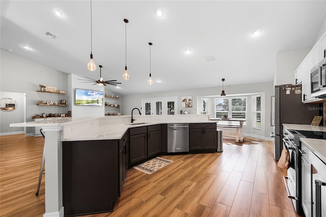 5478 NW 153rd Ct, Morriston, FL 32668 - kitchen featuring stainless steel appliances, light wood-style floors, a sink, decorative light fixtures, and a breakfast bar area
