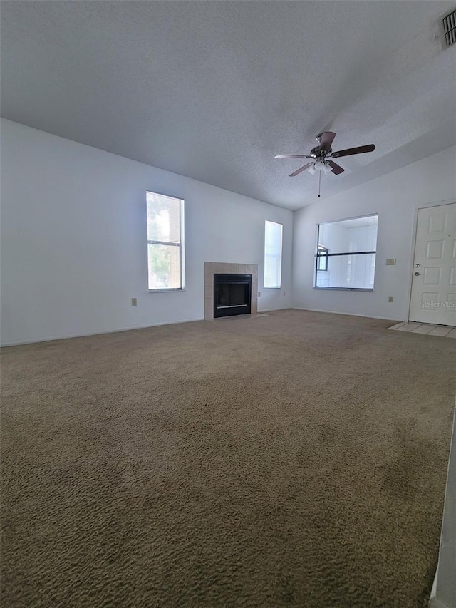 3124 S Semoran Blvd Unit 206, Orlando, FL 32822 - unfurnished living room featuring carpet flooring, a tiled fireplace, a ceiling fan, vaulted ceiling, and a textured ceiling