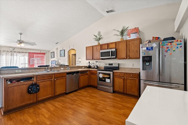 1321 Dunbarton Ct, Kissimmee, FL 34758 - kitchen featuring appliances with stainless steel finishes, vaulted ceiling, a textured ceiling, a sink, and brown cabinets