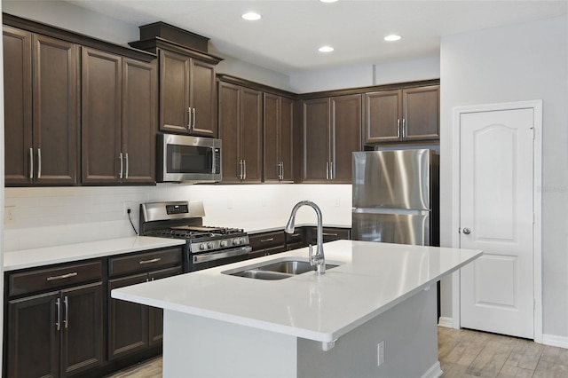328 Cedar Bark Ln, Sanford, FL 32771 - kitchen featuring appliances with stainless steel finishes, a sink, dark brown cabinets, light wood finished floors, and backsplash