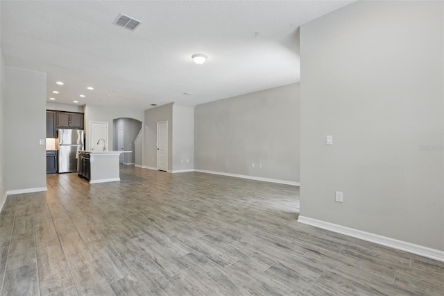 328 Cedar Bark Ln, Sanford, FL 32771 - unfurnished living room featuring arched walkways, a sink, light wood-type flooring, baseboards, and recessed lighting