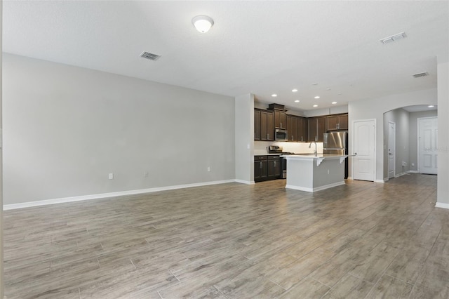 328 Cedar Bark Ln, Sanford, FL 32771 - unfurnished living room with arched walkways, baseboards, light wood-style flooring, recessed lighting, and a sink