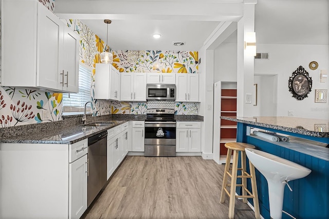 826 Cherokee Cir, Sanford, FL 32773 - kitchen featuring stainless steel appliances, a sink, white cabinetry, a breakfast bar area, and light wood-style flooring