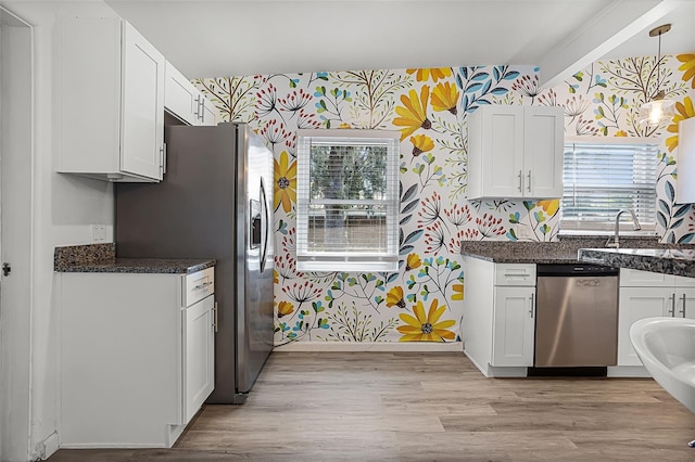 826 Cherokee Cir, Sanford, FL 32773 - kitchen featuring wallpapered walls, stainless steel appliances, white cabinetry, a sink, and light wood-type flooring