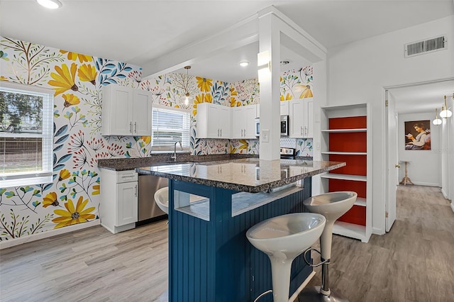 826 Cherokee Cir, Sanford, FL 32773 - kitchen featuring wallpapered walls, a kitchen bar, light wood-style flooring, white cabinets, and dishwasher