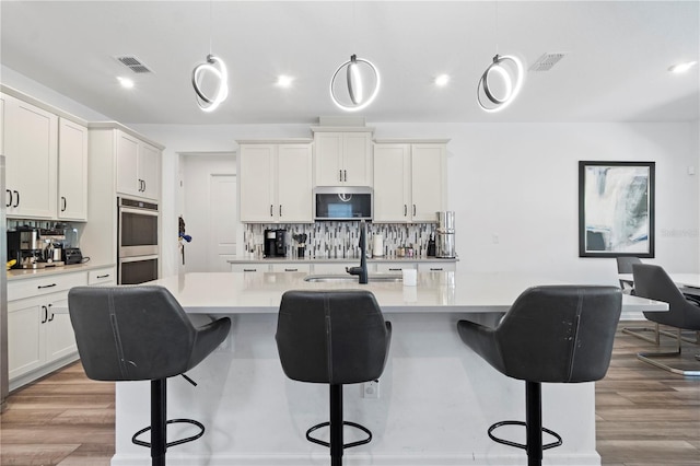 2227 Blue Salvia St, Clermont, FL 34711 - kitchen featuring stainless steel appliances, decorative backsplash, light countertops, a center island with sink, and recessed lighting