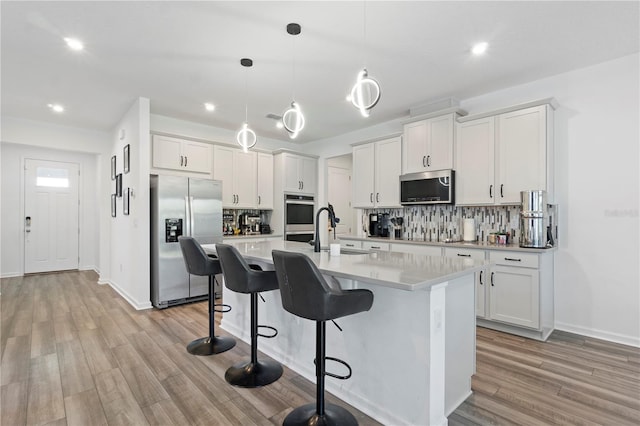2227 Blue Salvia St, Clermont, FL 34711 - kitchen featuring appliances with stainless steel finishes, decorative backsplash, light countertops, an island with sink, and recessed lighting