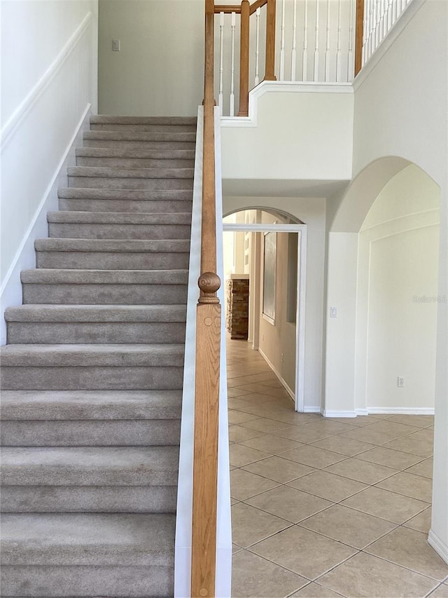 2143 Autumn View Dr, Orlando, FL 32825 - stairway with a towering ceiling, tile patterned flooring, arched walkways, and baseboards
