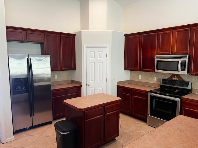 2143 Autumn View Dr, Orlando, FL 32825 - kitchen featuring stainless steel appliances, reddish brown cabinets, light tile patterned floors, and a high ceiling