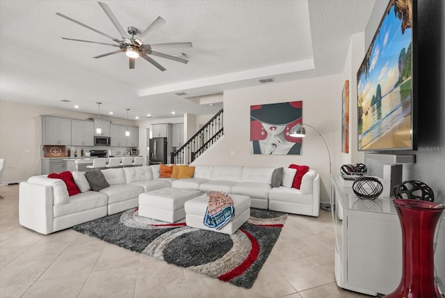 8811 Bally Neal Loop, Davenport, FL 33896 - living area with ceiling fan, stairs, light tile patterned floors, a tray ceiling, and baseboards