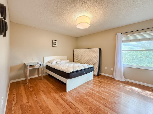 6047 Shore Line Dr, Orlando, FL 32819 - bedroom with light wood-type flooring, a textured ceiling, and baseboards