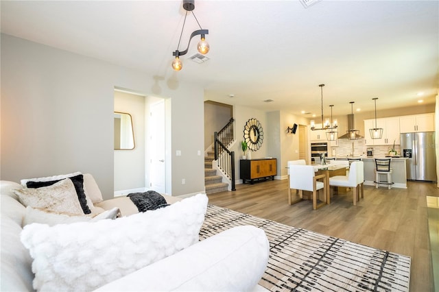 12259 Bracco St, Winter Garden, FL 34787 - living room with light wood-type flooring, stairs, recessed lighting, baseboards, and a chandelier