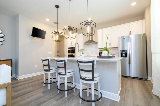 12259 Bracco St, Winter Garden, FL 34787 - kitchen with appliances with stainless steel finishes, tasteful backsplash, an island with sink, light wood-style flooring, and light countertops