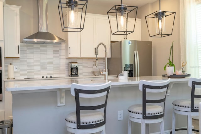 12259 Bracco St, Winter Garden, FL 34787 - kitchen featuring wall chimney exhaust hood, stainless steel fridge, black electric cooktop, decorative backsplash, and white cabinetry