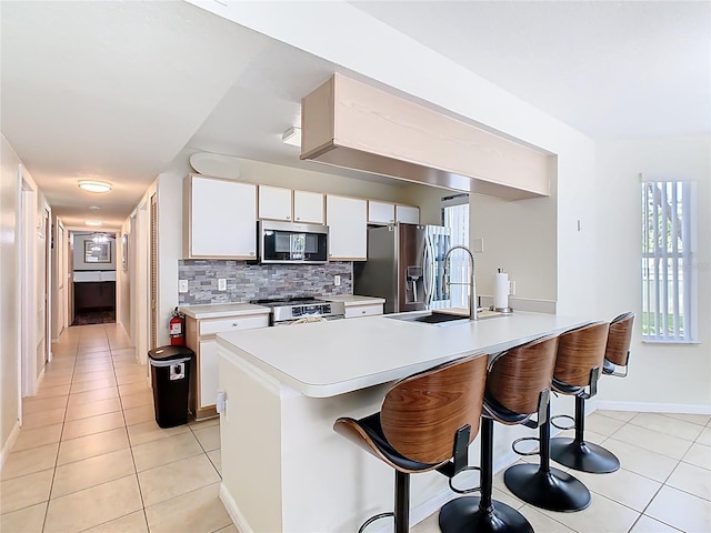 8704 Knightsbridge Ct Unit B, Kissimmee, FL 34747 - kitchen with appliances with stainless steel finishes, a peninsula, a kitchen breakfast bar, light countertops, and light tile patterned floors