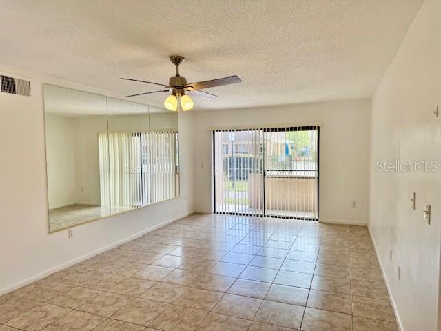 5269 Vineland Rd Unit 101, Orlando, FL 32811 - spare room featuring ceiling fan, a textured ceiling, light tile patterned flooring, and baseboards