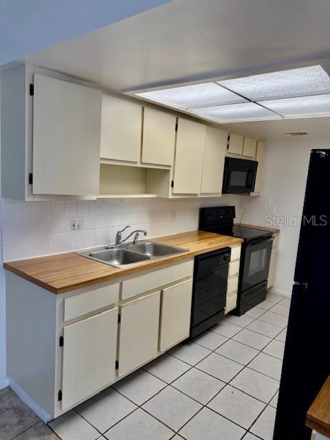 5269 Vineland Rd Unit 101, Orlando, FL 32811 - kitchen featuring black appliances, a sink, light tile patterned floors, and decorative backsplash