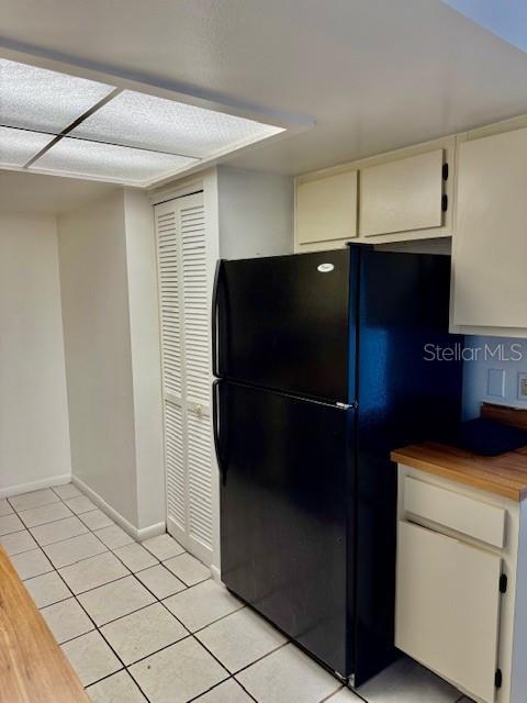 5269 Vineland Rd Unit 101, Orlando, FL 32811 - kitchen with freestanding refrigerator, light tile patterned flooring, baseboards, and wooden counters