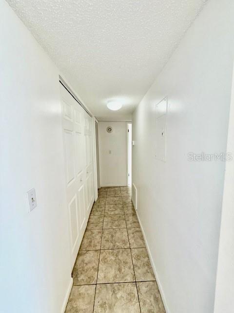 5269 Vineland Rd Unit 101, Orlando, FL 32811 - hall featuring a textured ceiling, light tile patterned floors, and baseboards