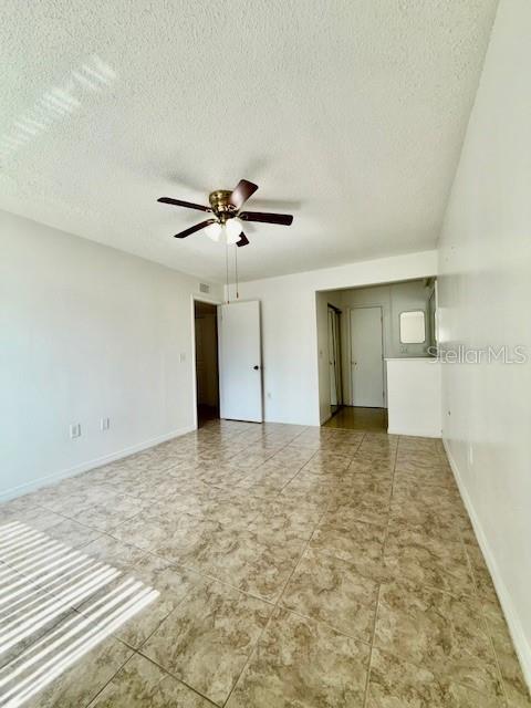 5269 Vineland Rd Unit 101, Orlando, FL 32811 - empty room featuring ceiling fan, a textured ceiling, and baseboards