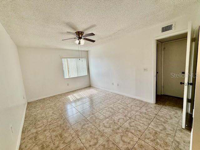 5269 Vineland Rd Unit 101, Orlando, FL 32811 - spare room featuring ceiling fan, a textured ceiling, light tile patterned flooring, and baseboards