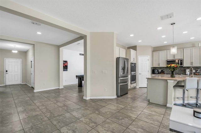 1821 Benevento St, Saint Cloud, FL 34771 - kitchen featuring appliances with stainless steel finishes, light tile patterned floors, decorative backsplash, light countertops, and recessed lighting