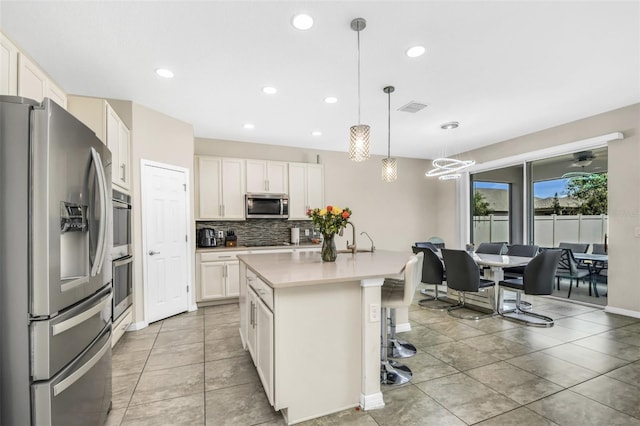 1821 Benevento St, Saint Cloud, FL 34771 - kitchen featuring stainless steel appliances, tasteful backsplash, a kitchen island with sink, recessed lighting, and light countertops