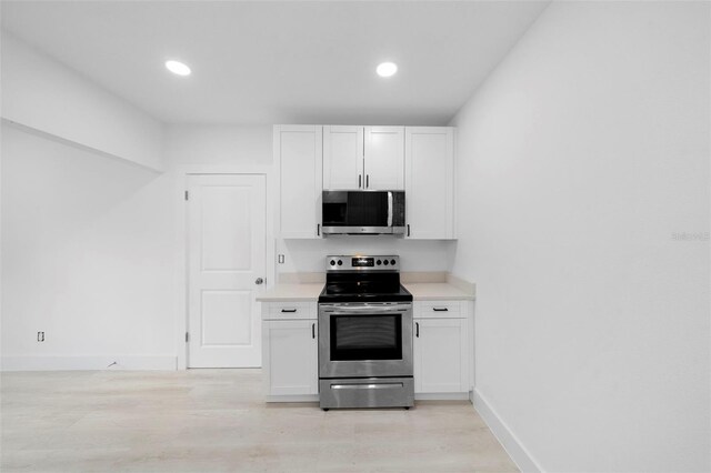 161 Bolender Rd, Auburndale, FL 33823 - kitchen with stainless steel appliances, light countertops, light wood-type flooring, baseboards, and white cabinets