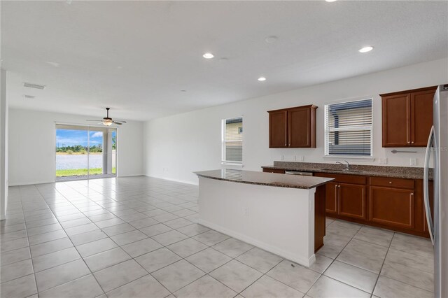 3953 Baja Dr, Saint Cloud, FL 34772 - kitchen featuring stainless steel appliances, ceiling fan, a center island, light tile patterned floors, and dark stone counters