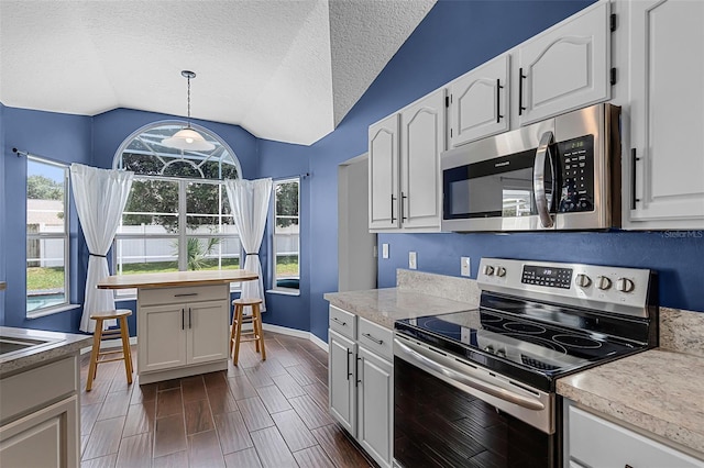 2203 Essex Dr, Ocoee, FL 34761 - kitchen with appliances with stainless steel finishes, lofted ceiling, light countertops, white cabinetry, and a textured ceiling