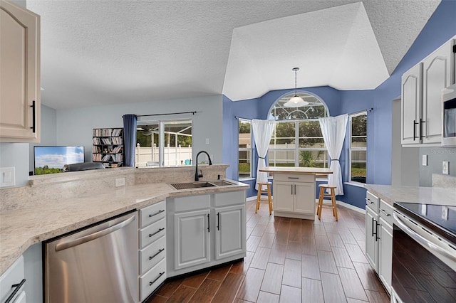 2203 Essex Dr, Ocoee, FL 34761 - kitchen featuring appliances with stainless steel finishes, a sink, vaulted ceiling, light countertops, and pendant lighting