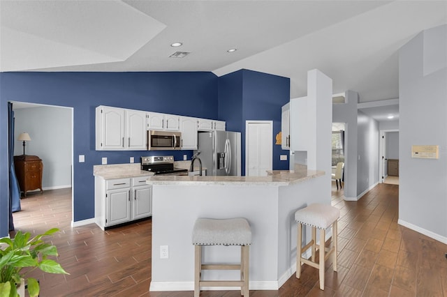 2203 Essex Dr, Ocoee, FL 34761 - kitchen with appliances with stainless steel finishes, baseboards, a breakfast bar, dark wood-style floors, and high vaulted ceiling