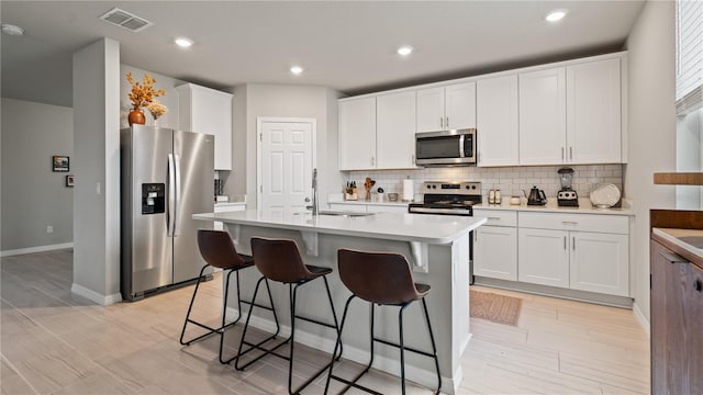5291 Meredrew Ln, Saint Cloud, FL 34771 - kitchen featuring stainless steel appliances, a sink, light countertops, a breakfast bar, and decorative backsplash